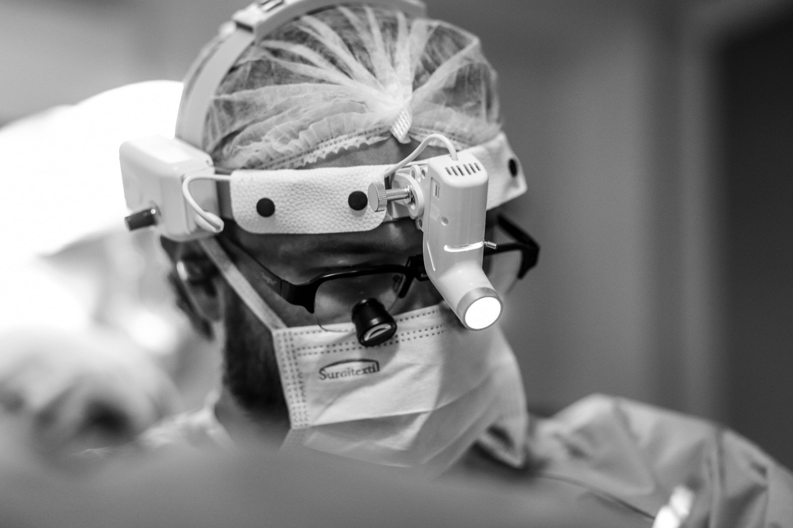 Dr. Otávio Taugen, cirurgião plástico, com lupas cirúrgicas durante procedimento